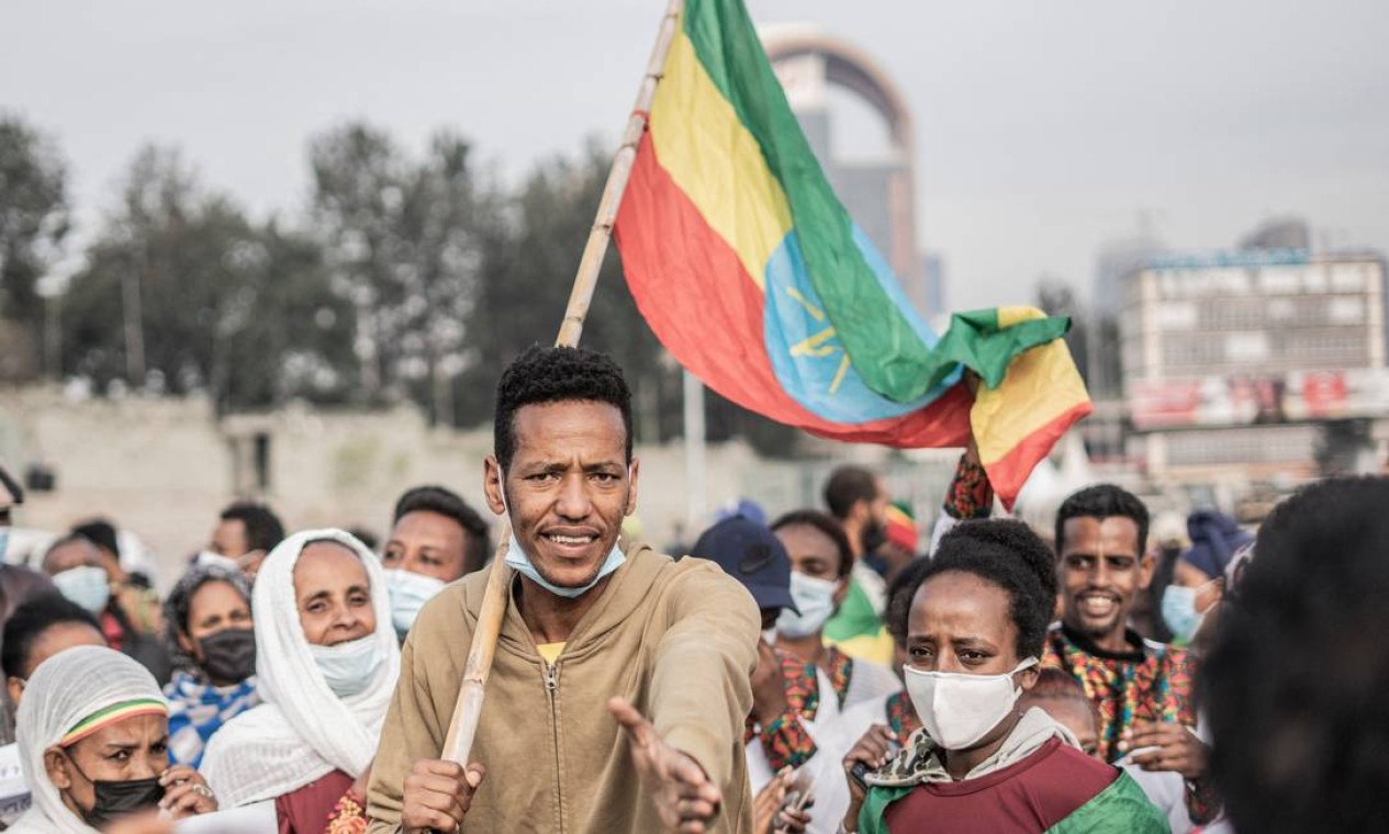 Homem segura uma bandeira nacional da Etiópia, na capital Addis Abeba, durante uma cerimônia realizada para apoiar os militares etíopes que estão lutando contra a Frente de Libertação do Povo Tigray Foto: AMANUEL SILESHI / AFP
