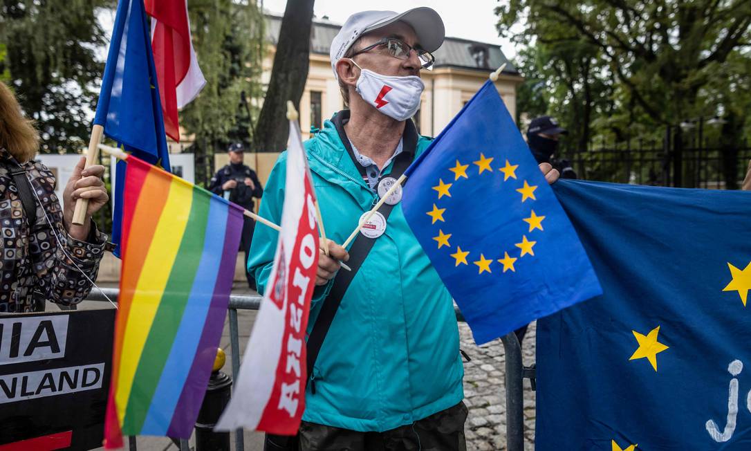 Um manifestante segura bandeiras LGBTQIAP+, da Polônia e da UE durante protesto em frente ao Tribunal Constitucional em Varsóvia Foto: WOJTEK RADWANSKI / AFP/31-08-2021