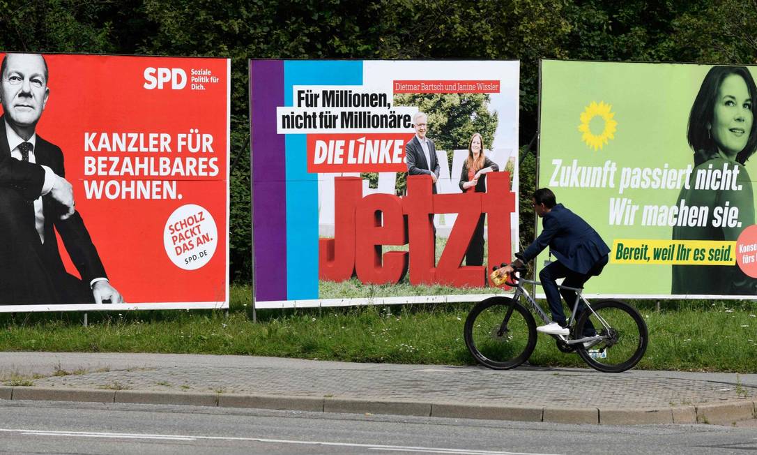 Cartaz do Die Linke entre propaganda eleitoral de Olaf Scholz, o candidato social-democrata, e de Annalena Baerbock, do Partido Verde, em Stuttgart Foto: THOMAS KIENZLE / AFP