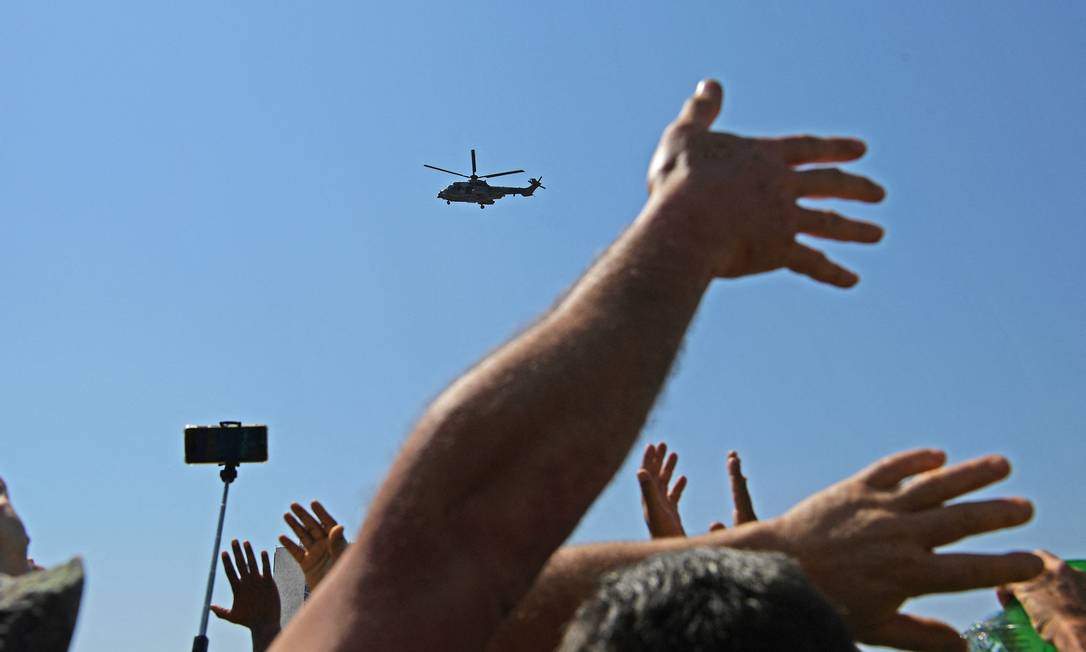 Apoiadores acenam para Bolsonaro, a bordo de helicóptero da Força Aérea Brasileira, em Brasília Foto: CARL DE SOUZA / AFP