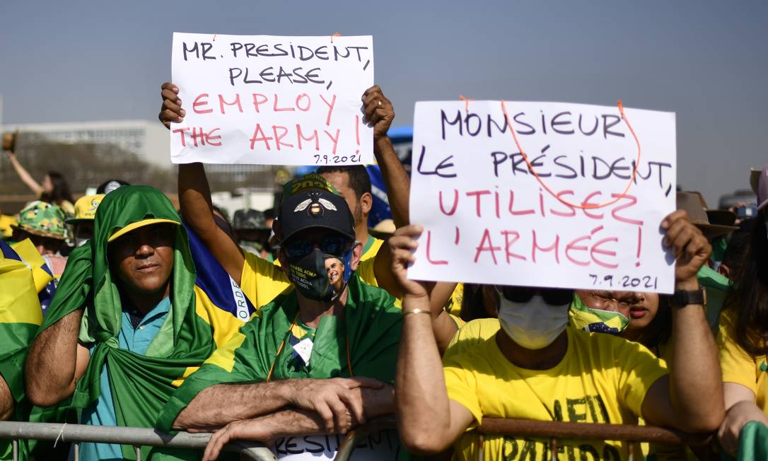 Apoiadores do presidente Bolsonaro seguram cartazes com a mensagem: 