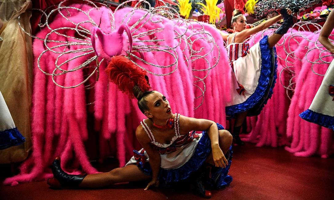 Dançarinas se alongam antes de subirem ao palco do Moulin Rouge, num dos ensaios que antecederam a reabertura do teatro em Paris, após 18 meses Foto: CHRISTOPHE ARCHAMBAULT / AFP