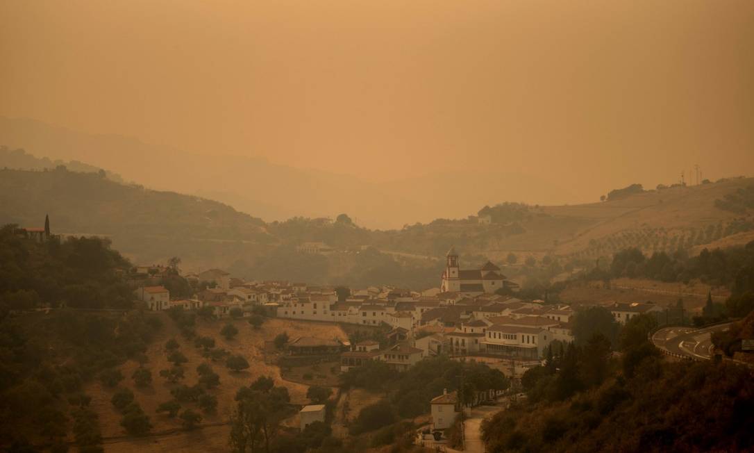 A fumaça toma o céu do vilarejo de Atajate enquanto as chamas se espalham pela Sierra Bermeja Foto: JORGE GUERRERO / AFP