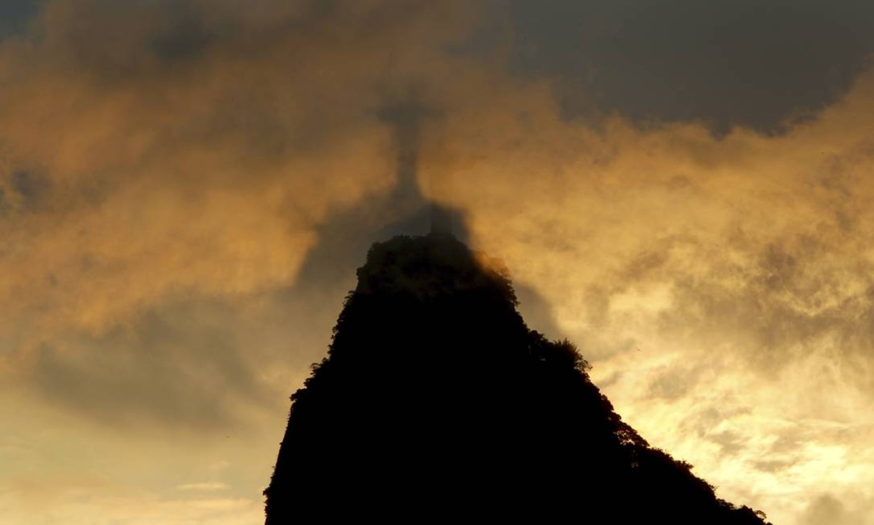 Silhueta do Cristo é vista através de nuvens que cobrem o cume da pedra do Corcovado Foto: Custódio Coimbra / Agência O Globo - 19/12/2017