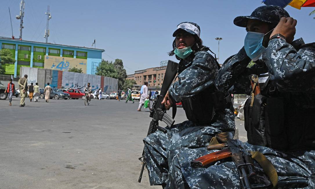 Usando uniformes das antigas forças de segurança afegãs, milicianos do Talibã patrulham rua de Cabul Foto: AAMIR QURESHI / AFP