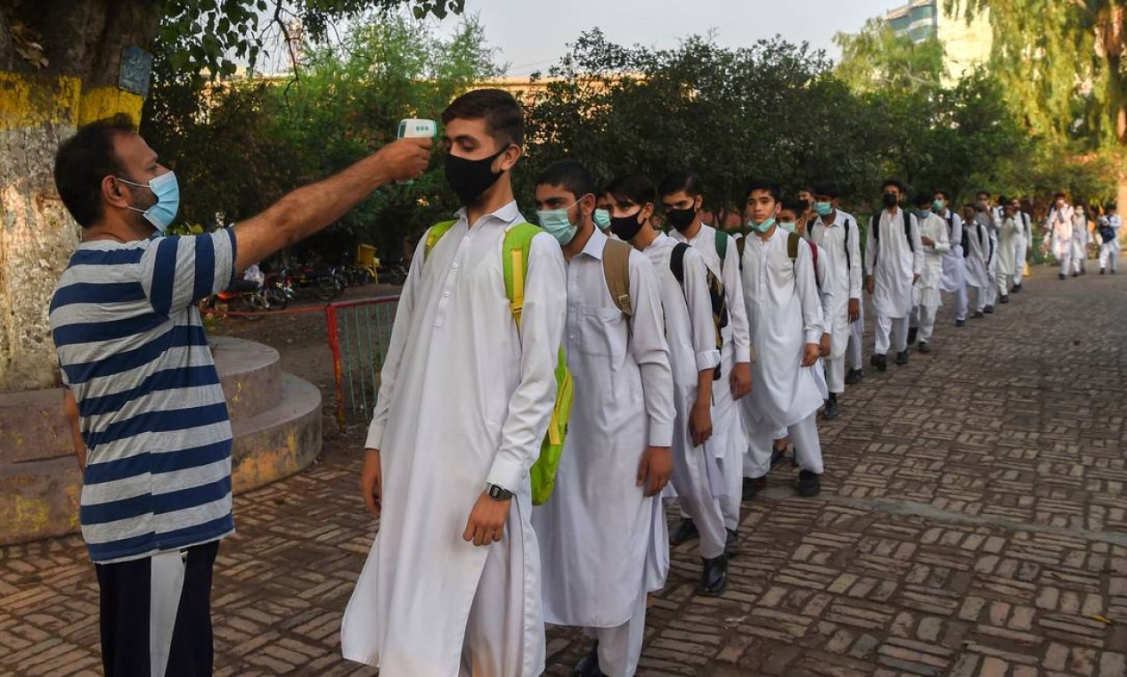 Professor mede a temperatura de alunos em Pexaua, no Paquistão Foto: ABDUL MAJEED / AFP