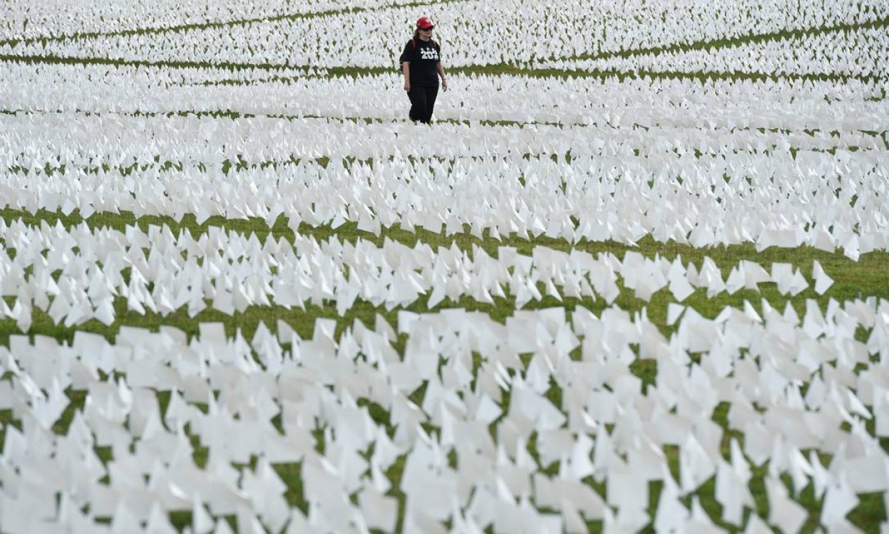 Mulher caminha pelo campo de bandeiras brancas perto do Monumento a Washington, em Washington, DC Foto: MANDEL NGAN / AFP