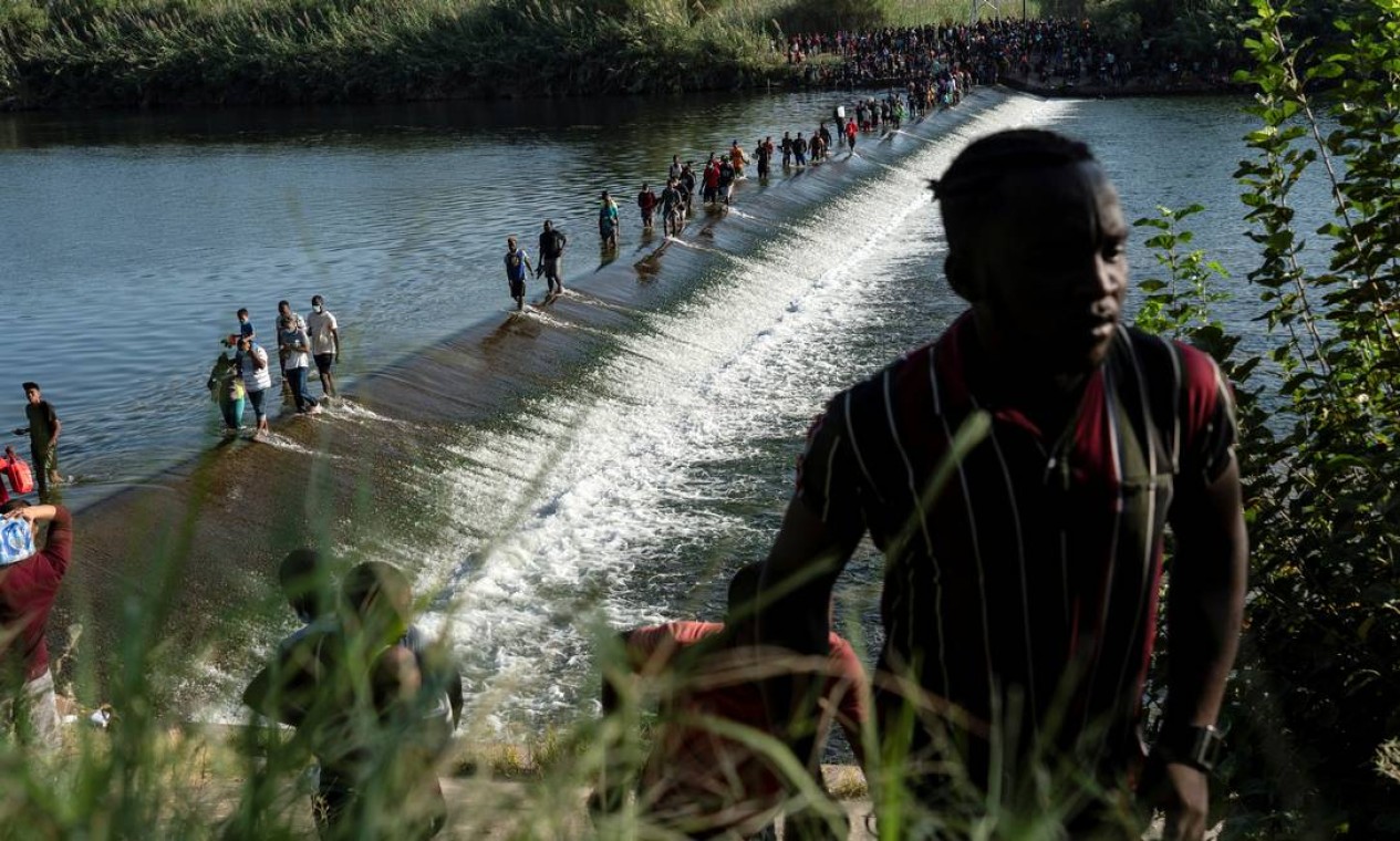 Migrantes que procuram asilo nos EUA caminham no Rio Grande, próximo à Ponte Internacional entre o México e os EUA Foto: GO NAKAMURA / REUTERS