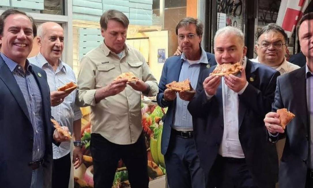 Bolsonaro come pizza na calçada em Nova York, com ministros, em setembro: sem estar vacinado, presidente não poderia entrar em restaurantes da cidade Foto: Reprodução