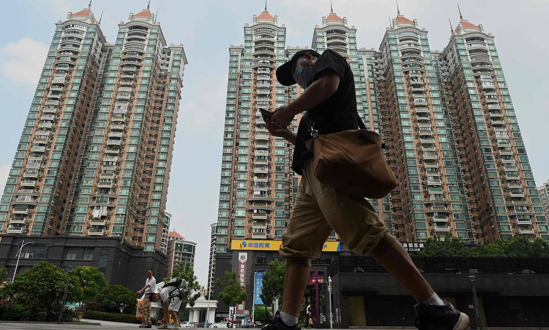 Homem passa em frente a condomínio desenvolvido pela chinesa Evergrande, em Guangzhou, no sul da China: empresa deve dar calote em investidores, fornecedores e clientes Foto: Noel Celis / AFP