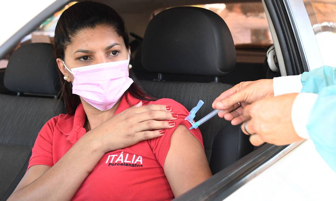Mulher é vacinada em posto drive-thru, em Brasília Foto: EVARISTO SA / AFP