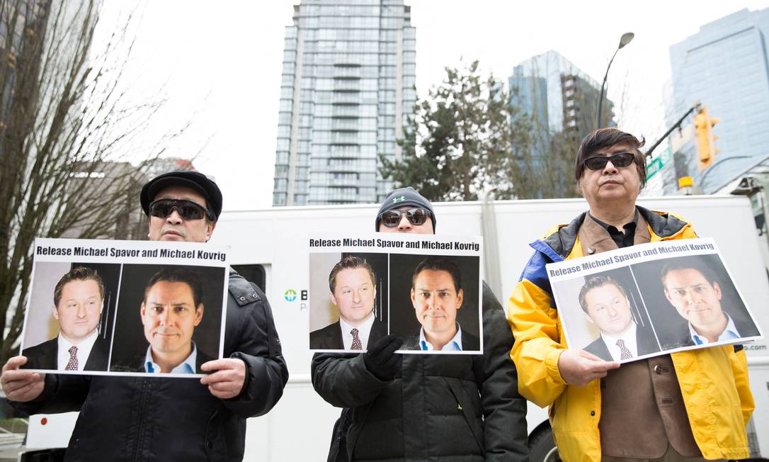 Manifestantes carregam cartazes com as imagens de Michael Spavor e Michael Kovrig, canadenses presos na China, durante protesto em Vancouver Foto: JASON REDMOND / AFP