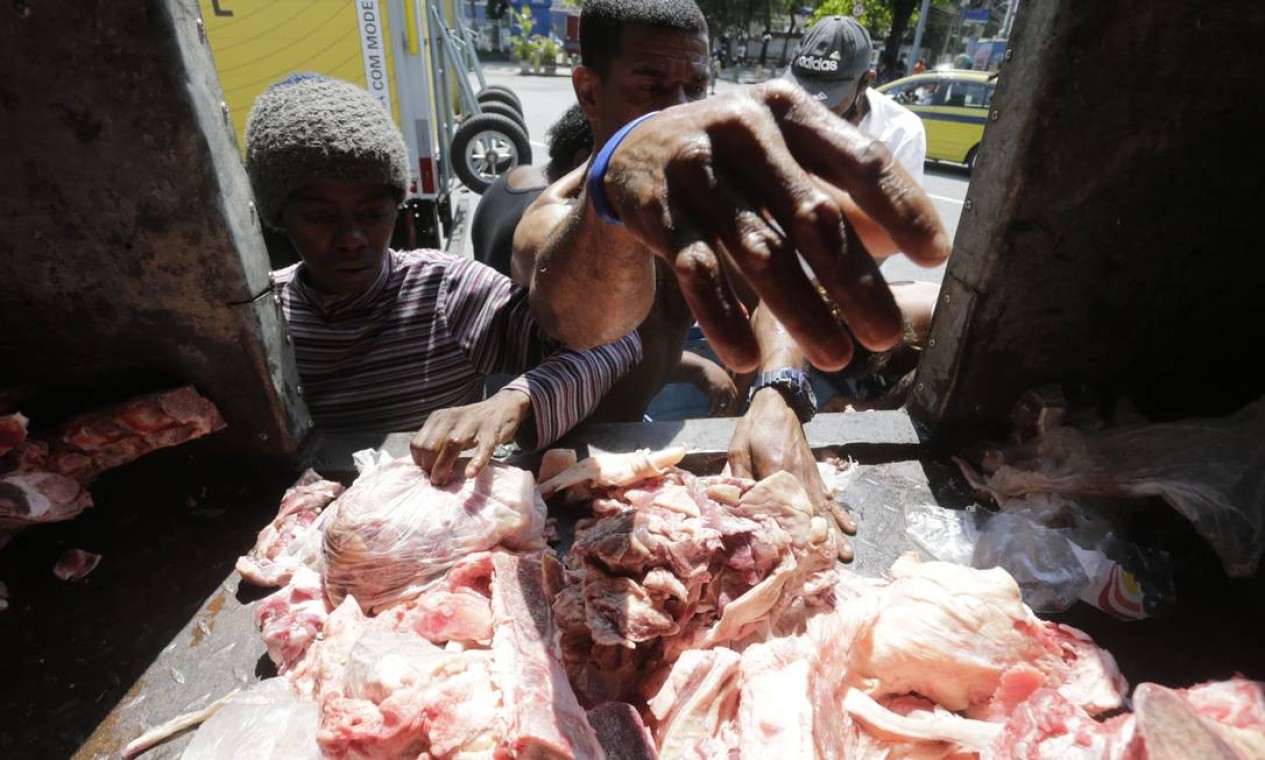 Fila da fome. Pessoas em situação de rua disputam restor de carne em caminhão. Foto: Domingos Peixoto / Agência O Globo