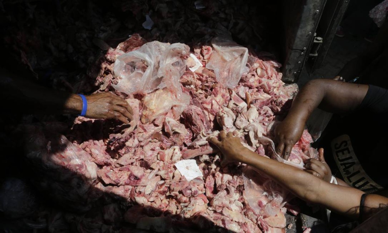 População seleciona porções do que restou da carne dos mercados Foto: Domingos Peixoto / Agência O Globo