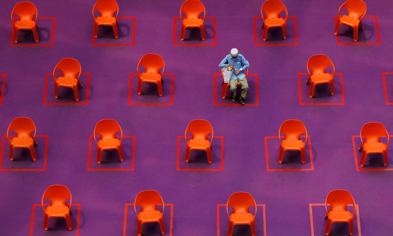 Um homem senta-se entre os assentos vazios em uma exibição de filme gratuita enquanto as restrições à reunião social são aumentadas devido ao aumento de casos do surto de COVID-19, em Cingapura Foto: EDGAR SU / REUTERS