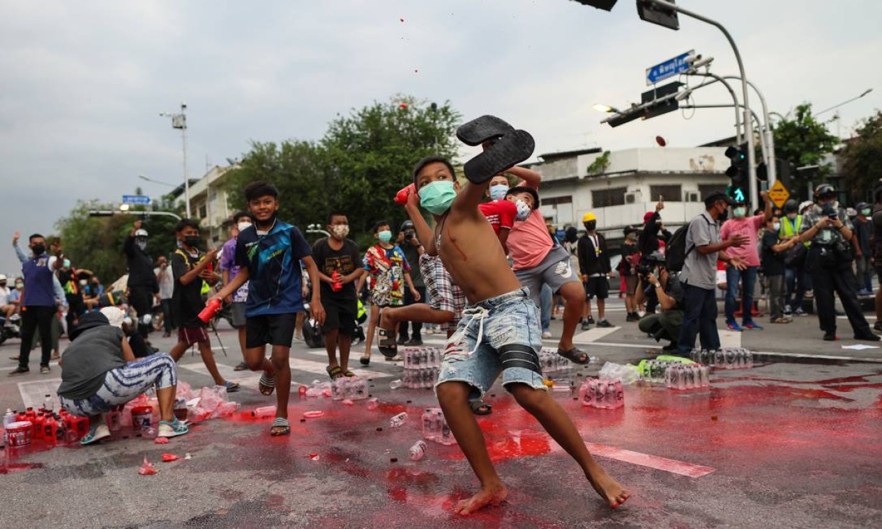 Manifestantes atiram garrafas de tinta vermelha na polícia durante protesto, em Bangkok, contra o primeiro-ministro da Tailândia, Prayut Chan-O-Cha, por causa das políticas do governo contra a Covid-19 Foto: JACK TAYLOR / AFP
