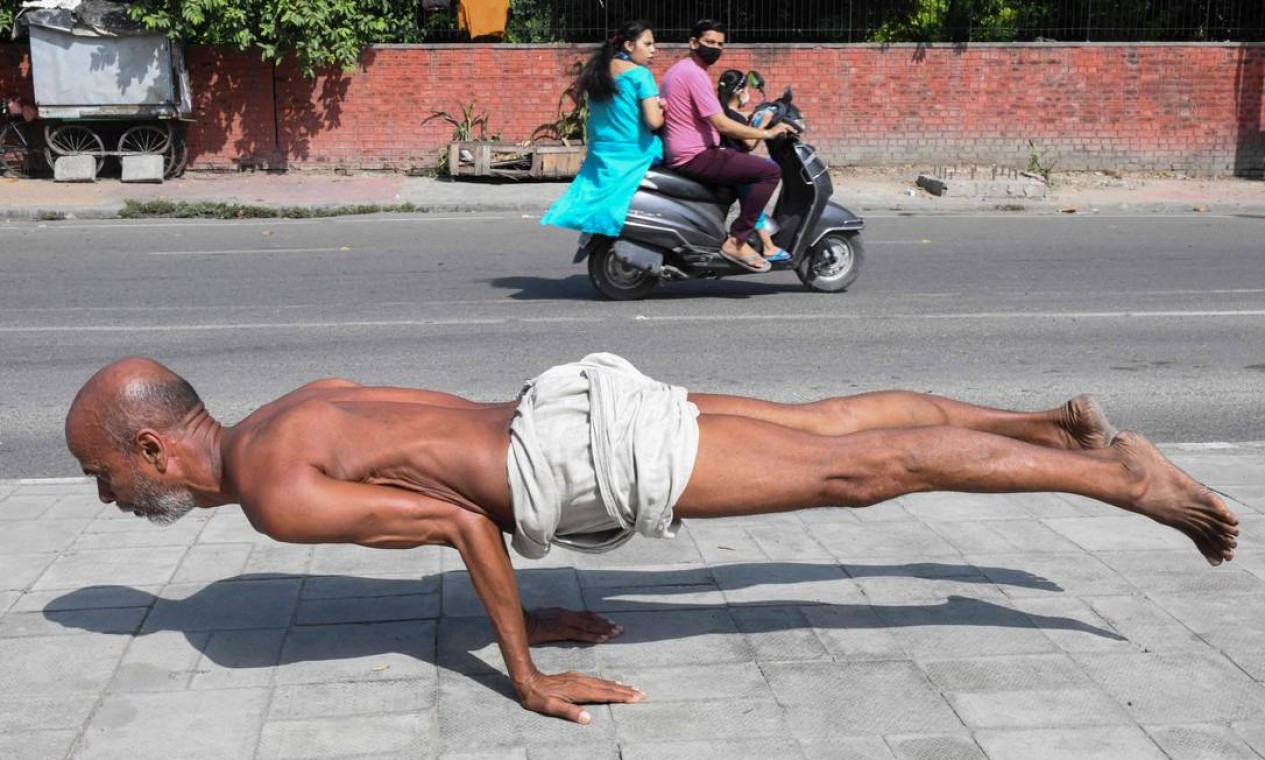 TOPSHOT - Um homem pratica ioga numa calçada de Amristar, na Índia Foto: NARINDER NANU / AFP