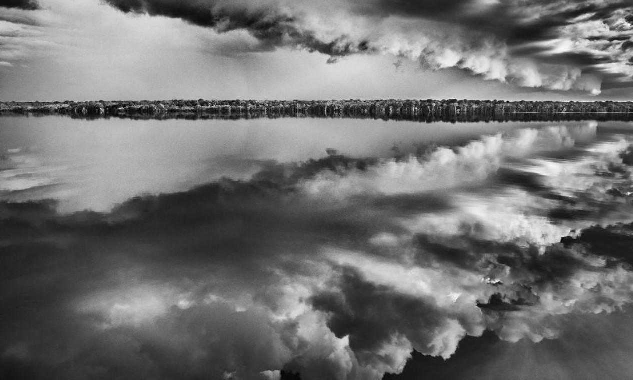 Diante do arquipélago de Mariuá, no Médio Rio Negro, a imagem das nuvens se reflete nas águas escuras do Rio Negro Foto: Sebastião SALGADO / Divulgação