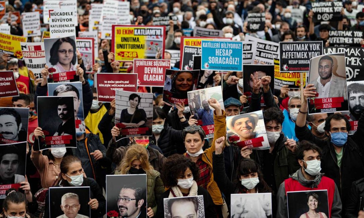 Pessoas seguram cartazes e retratos de vítimas durante um comício para marcar seis anos de um duplo atentado suicida que deixou 104 pessoas mortas em Istambul, em 2015 Foto: YASIN AKGUL / AFP