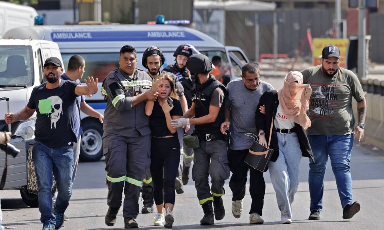 Médicos libaneses ajudam a evacuar civis durante confrontos na área de Tayouneh, no subúrbio ao sul da capital Beirute. Tiroteios mataram pelo menos três pessoas e feriram 20 Foto: JOSEPH EID / AFP