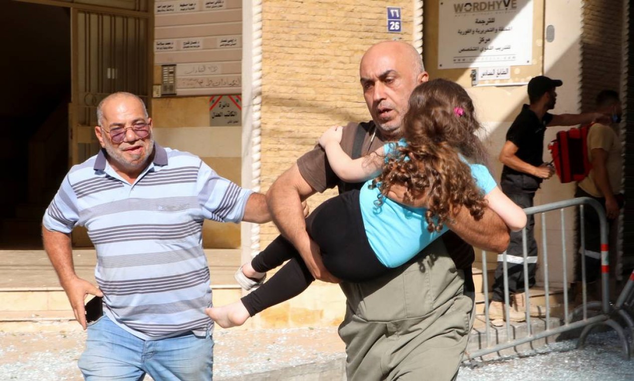 Homem carrega menina para tentar se proteger após o início do tiroteio Foto: MOHAMED AZAKIR / REUTERS