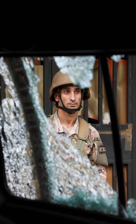 Soldado do exército é visto atrás de um vidro estilhaçado, após o tiroteio Foto: MOHAMED AZAKIR / REUTERS