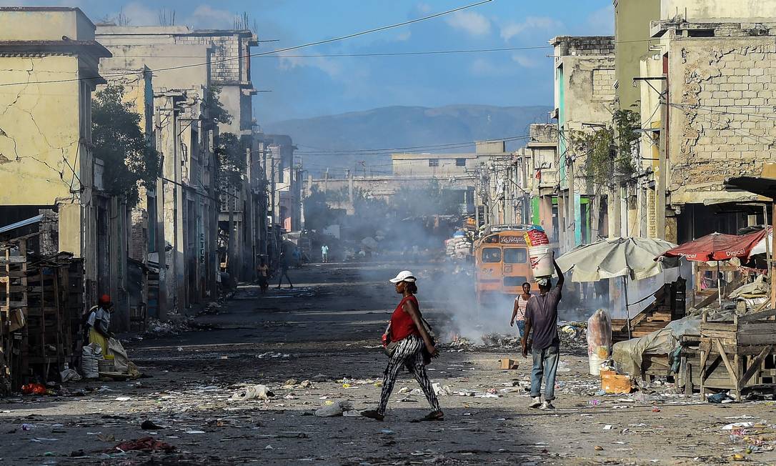 Pessoas caminham em estrada deserta antes de tiroteios de gangues no centro de Porto Príncipe, Haiti Foto: CHANDAN KHANNA / AFP/20-12-2019