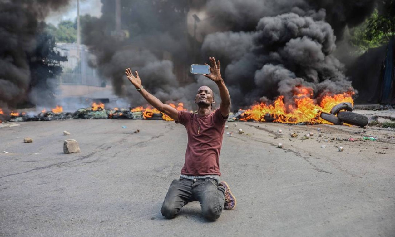 Homem se filma diante de barricada de pneus em chamas durante greve geral, em Porto Príncipe Foto: RICHARD PIERRIN / AFP