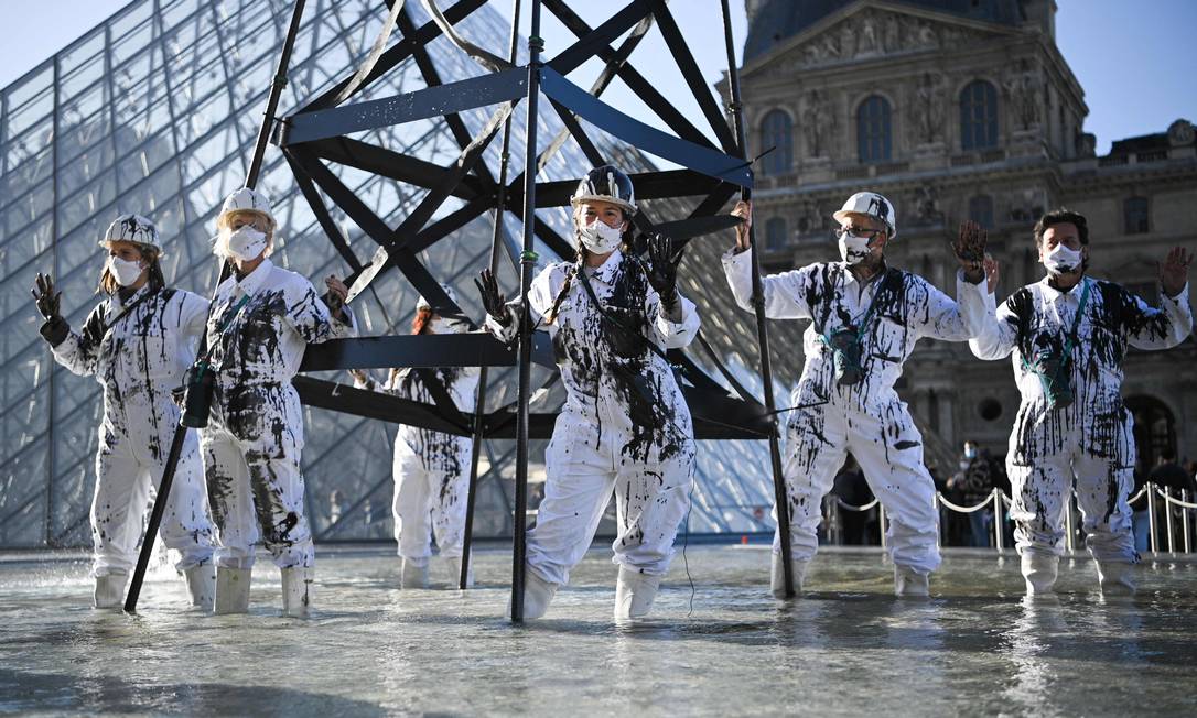 Ativistas do Greenpeace vestem uniforme de trabalhadores do petróleo durante ato no Museu do Louvre Foto: ANNE-CHRISTINE POUJOULAT / AFP/06-10-2021