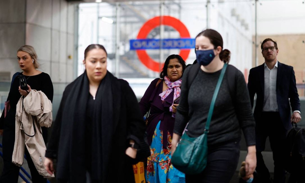 Passageiros, alguns usando coberturas faciais para ajudar a prevenir a disseminação do coronavírus, saem da estação de trem subterrâneo Transport for London (TfL) em Londres Foto: TOLGA AKMEN / AFP