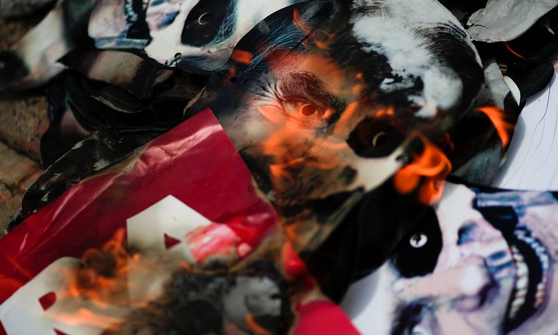 Máscaras com o presidente Bolsonaro representado como a morte são queimadas durante protesto Foto: UESLEI MARCELINO / REUTERS