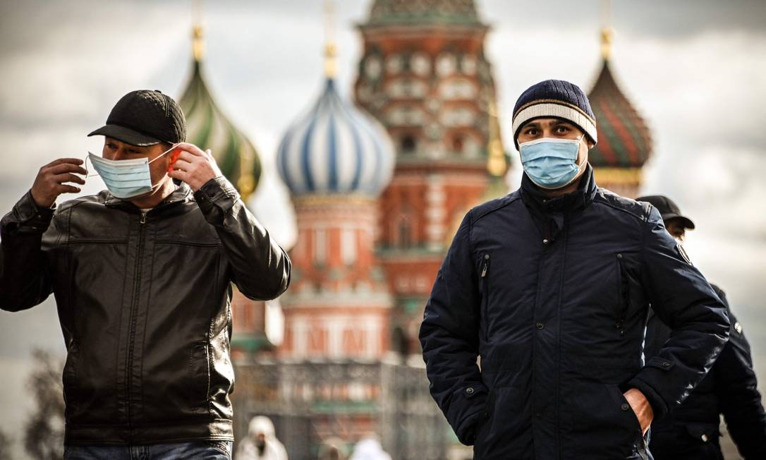 Turistas usam máscaras enquanto caminham pela Praça Vermelha, em Moscou, na Rússia Foto: ALEXANDER NEMENOV / AFP
