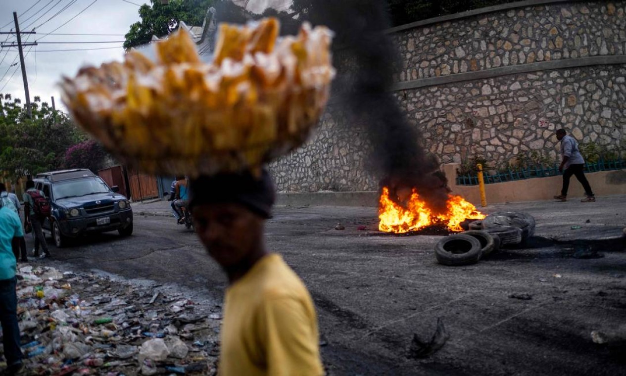 Vendedor de rua passa por uma barricada de pneus em chamas durante uma manifestação contra os altos preços e a escassez de combustível em Porto Príncipe, Haiti Foto: RICARDO ARDUENGO / AFP