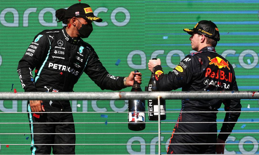 Max Verstappen e Lewis Hamilton se cumprimentam no pódio do GP dos EUA: holandês chegou em primeiro, à frente do inglês Foto: Chris Graythen / AFP