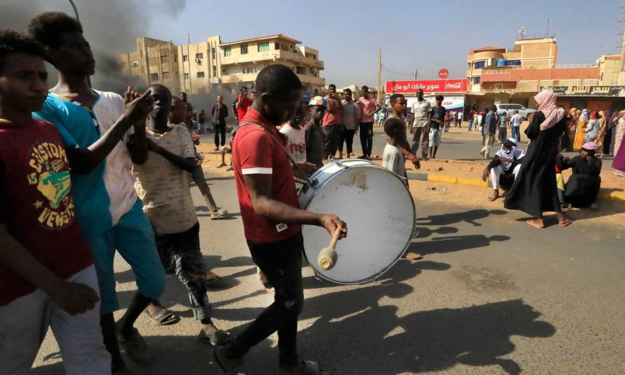 Jovem sudanês toca um tambor durante protesto que bloqueia uma estrada na capital do país Foto: AFP