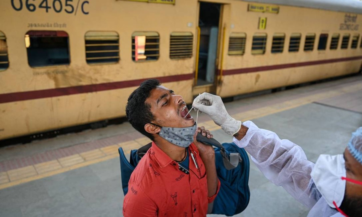 Profissional de saúde coleta uma amostra para testagem de coronavírus em uma plataforma ferroviária, em Mumbai, Índia Foto: PUNIT PARANJPE / AFP