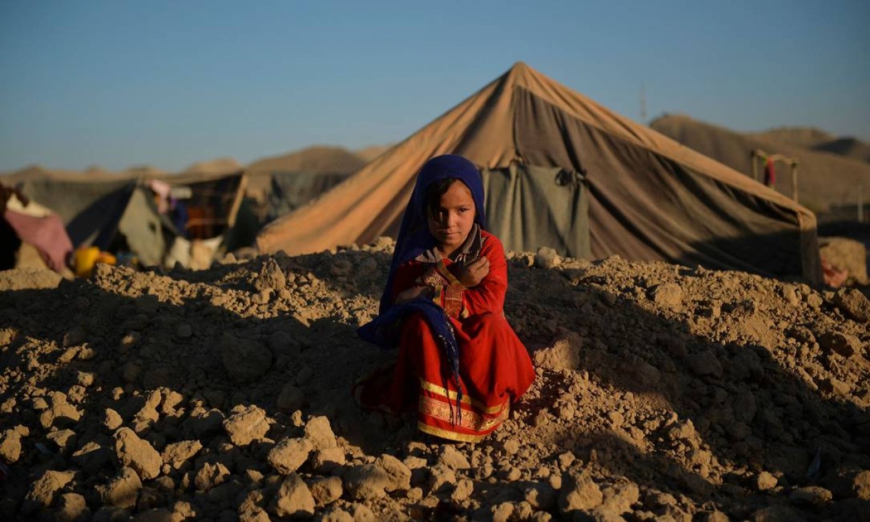 Asho, uma garotinha noiva de um homem de 23 anos cuja família tinha dívidas, senta do lado de fora de uma tenda no campo de deslocados internos, na província de Badghis. A guerra e a pobreza relacionada levam famílias a recorrer a acordos firmes cada vez mais cedo Foto: HOSHANG HASHIMI / AFP