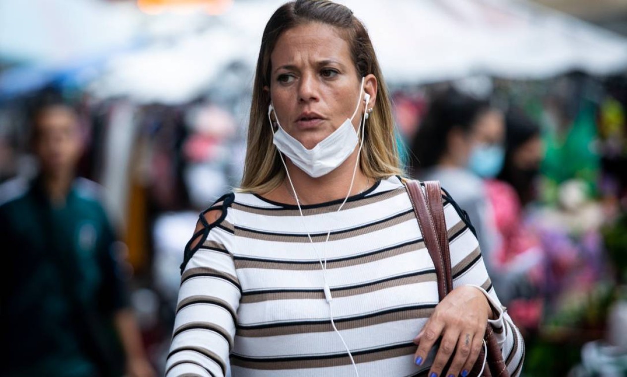 Mulher caminha por rua da Zona Sul com máscara no queixo Foto: Brenno Carvalho / Agência O Globo