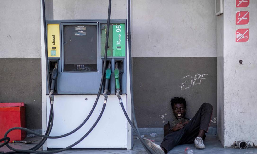Homem deita ao lado de bomba de combustível em um posto de gasolina fechado, em meio a uma escassez de combustível em Porto Príncipe Foto: RICARDO ARDUENGO / AFP