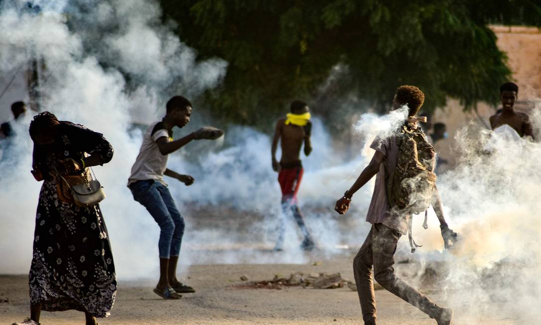 Jovens sudanses em protestos em meio a bombas de gás lacrimogêneo disparado para dispersar as manifestações na capital Cartum Foto: AFP