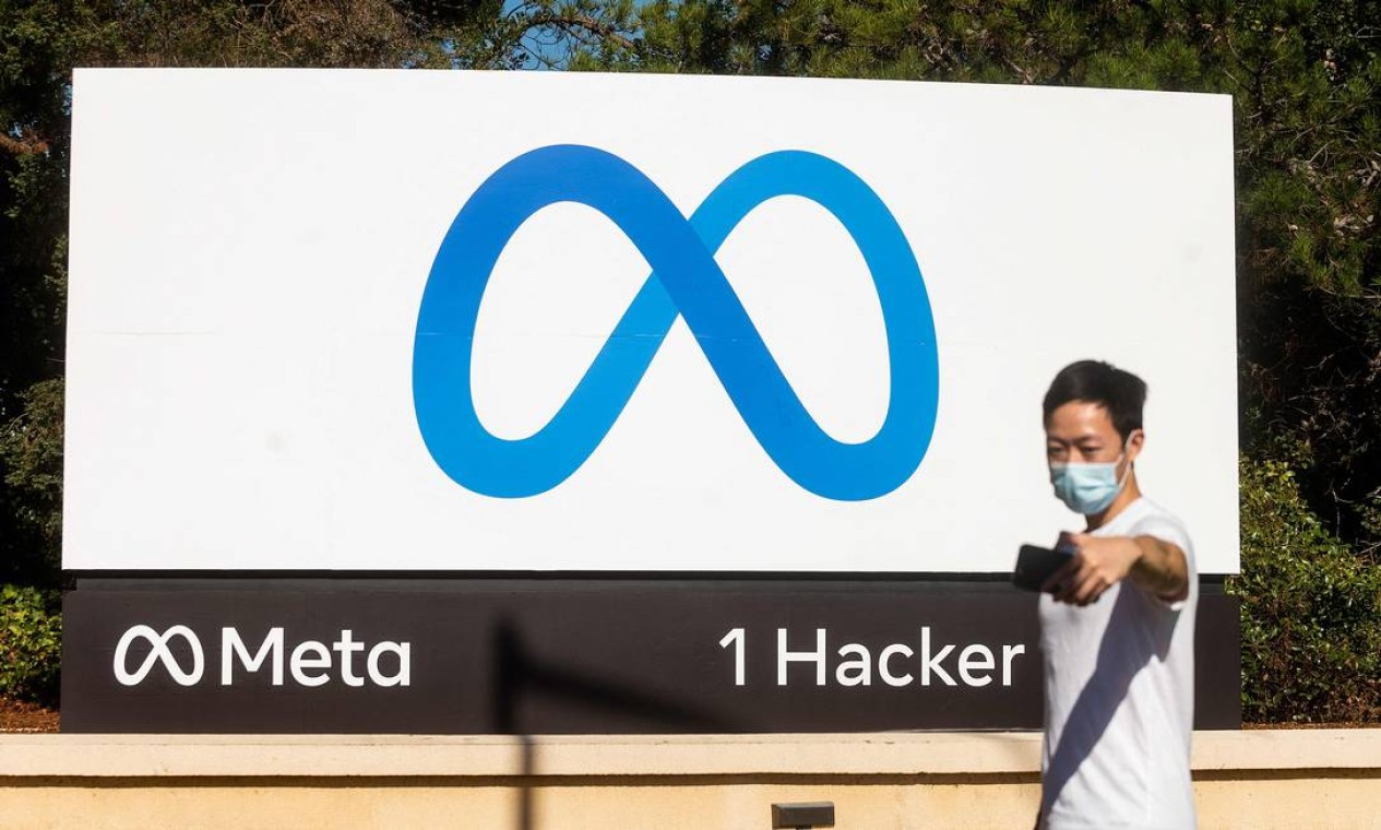 Pessoa tira selfie na frente de um logotipo recém-revelado de "Meta", o novo nome da empresa-mãe do Facebook, em Menlo Park, Califórnia Foto: NOAH BERGER / AFP