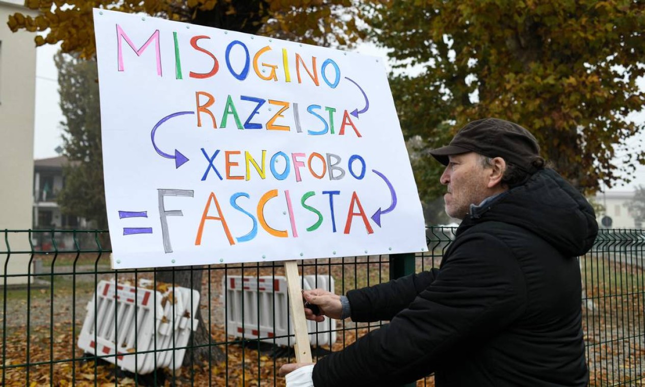 Um homem segura um cartaz com os dizeres "misógino, racista, xenófobo, fascista" durante uma reunião de protesto contra o presidente Jair Bolsonaro em 1º de novembro de 2021 em Anguillara Veneta, nordeste da Itália Foto: PIERO CRUCIATTI / AFP