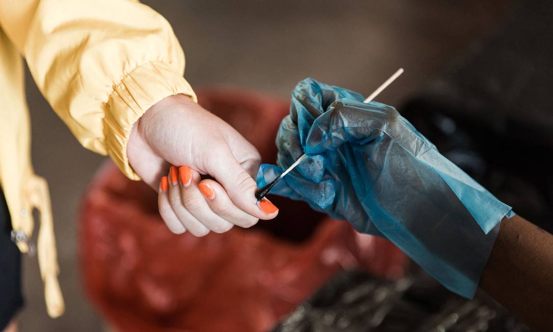 Eleitor tem seu dedo marcado com tinta especial depois de lançar sua cédula na seção eleitoral na Northwood Boys High School, em Durban, durante as eleições locais da África do Sul Foto: RAJESH JANTILAL / AFP