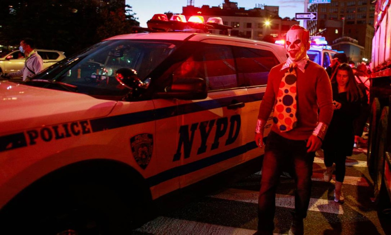 Varro da polícia de Nova York passa por pessoas fantasiadas que participam do desfile anual West Village Halloween Foto: KENA BETANCUR / AFP