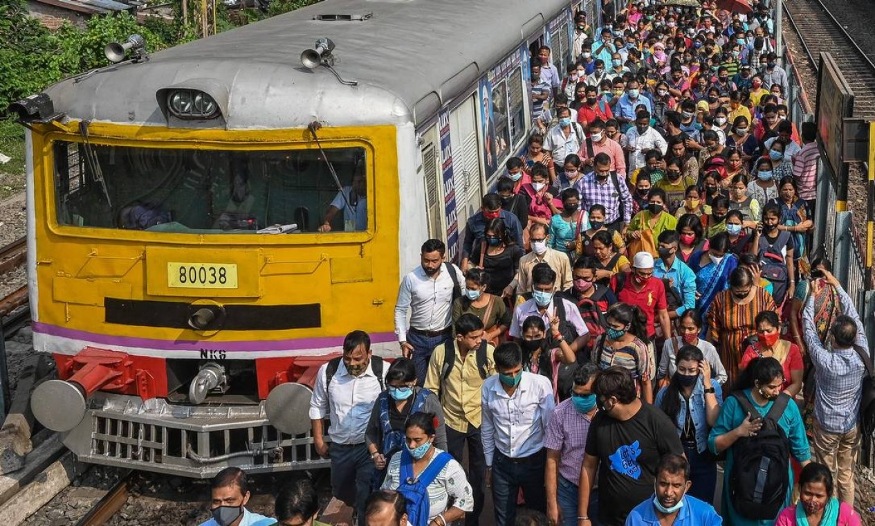 Passageiros caminham ao longo de plataforma ferroviária depois de desembarcar de trem suburbano em Calcutá. Oserviço retoma a normalidade após cumprir as restrições impostas anteriormente para conter a disseminação do coronavírus Covid-19 na Índia Foto: DIBYANGSHU SARKAR / AFP