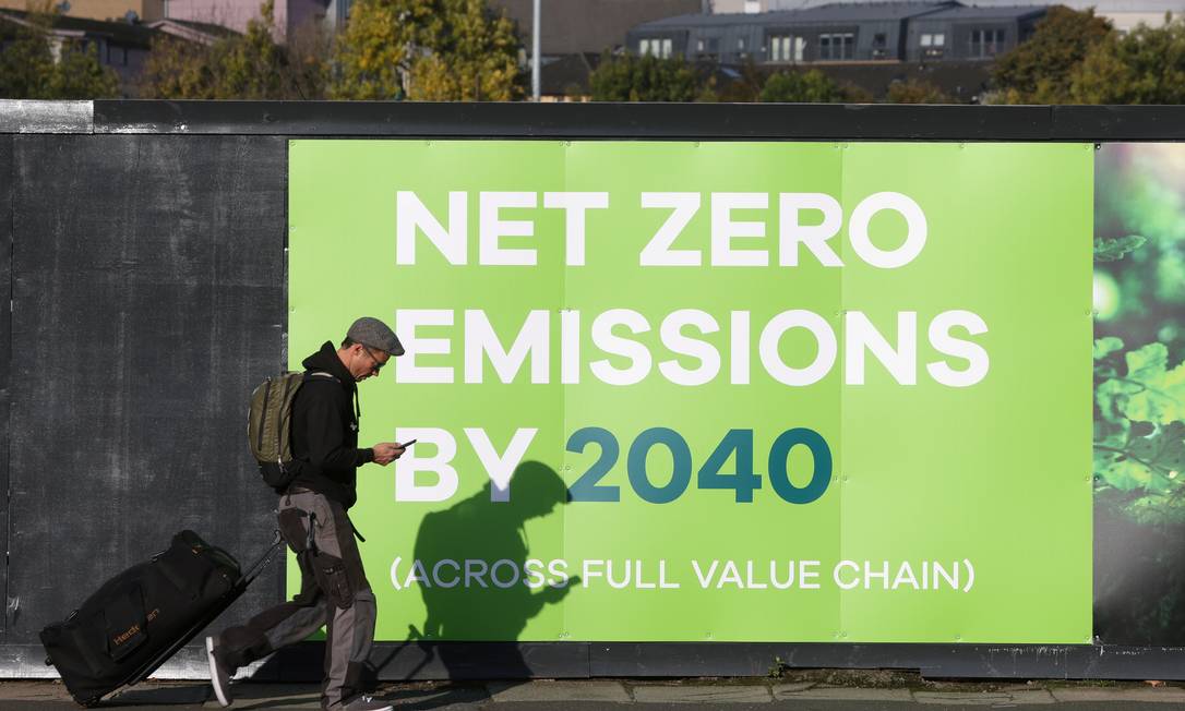 Homem passa por uma propaganda relacionada à Conferência das Nações Unidas sobre Mudança Climática (COP 26) em Glasgow Foto: YVES HERMAN / REUTERS