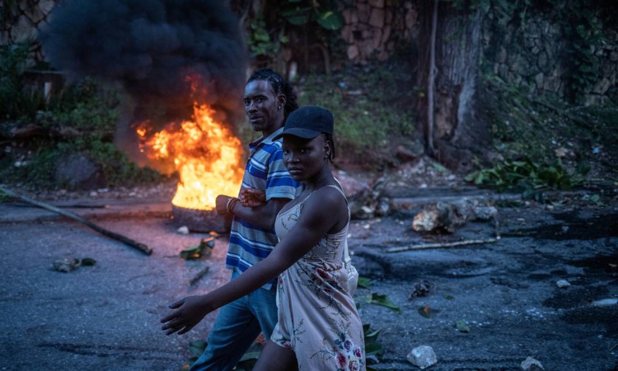 Casal passa por barricada em chamas armada para protestar contra um recente sequestro e tiroteio no bairro de Petionville, em Porto Príncipe, Haiti Foto: ADREES LATIF / REUTERS