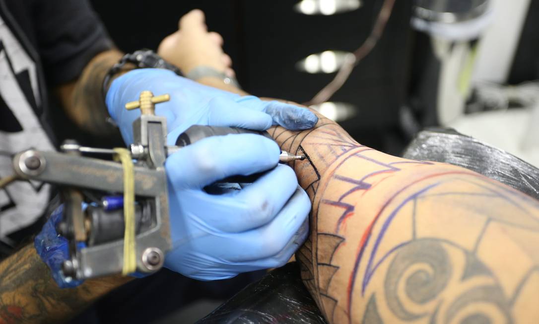 Artista tatua braço de cliente com tinta convencional no estúdio Banzai no Rio de Janeiro Foto: Pedro Teixeira / Agência O Globo/02-08-2018