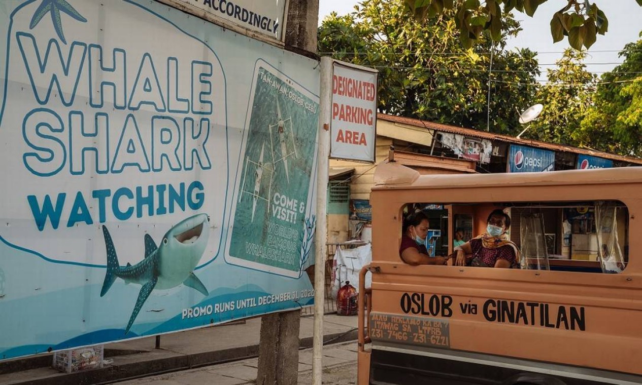 Cartaz anuncia a observação de tubarões-baleia no município de Oslob, do qual Tan-Awan faz parte: os animais viraram a grande atração turística da região nos últimos anos Foto: Hannah Reyes Morales / The New York Times