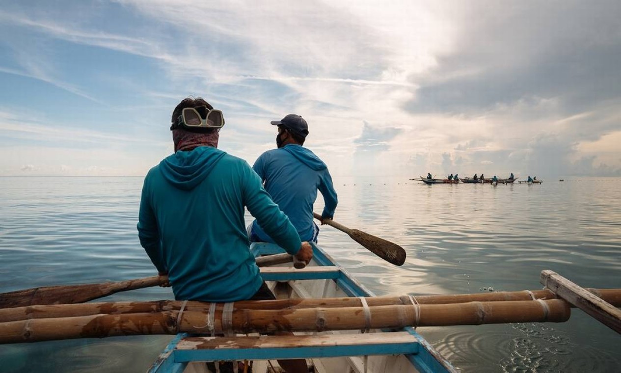 Pescadores de Tan-Awan, nas Filipinas, remam em suas canoas até a região onde os tubarões-baleia costumam ficar Foto: Hannah Reyes Morales / The New York Times